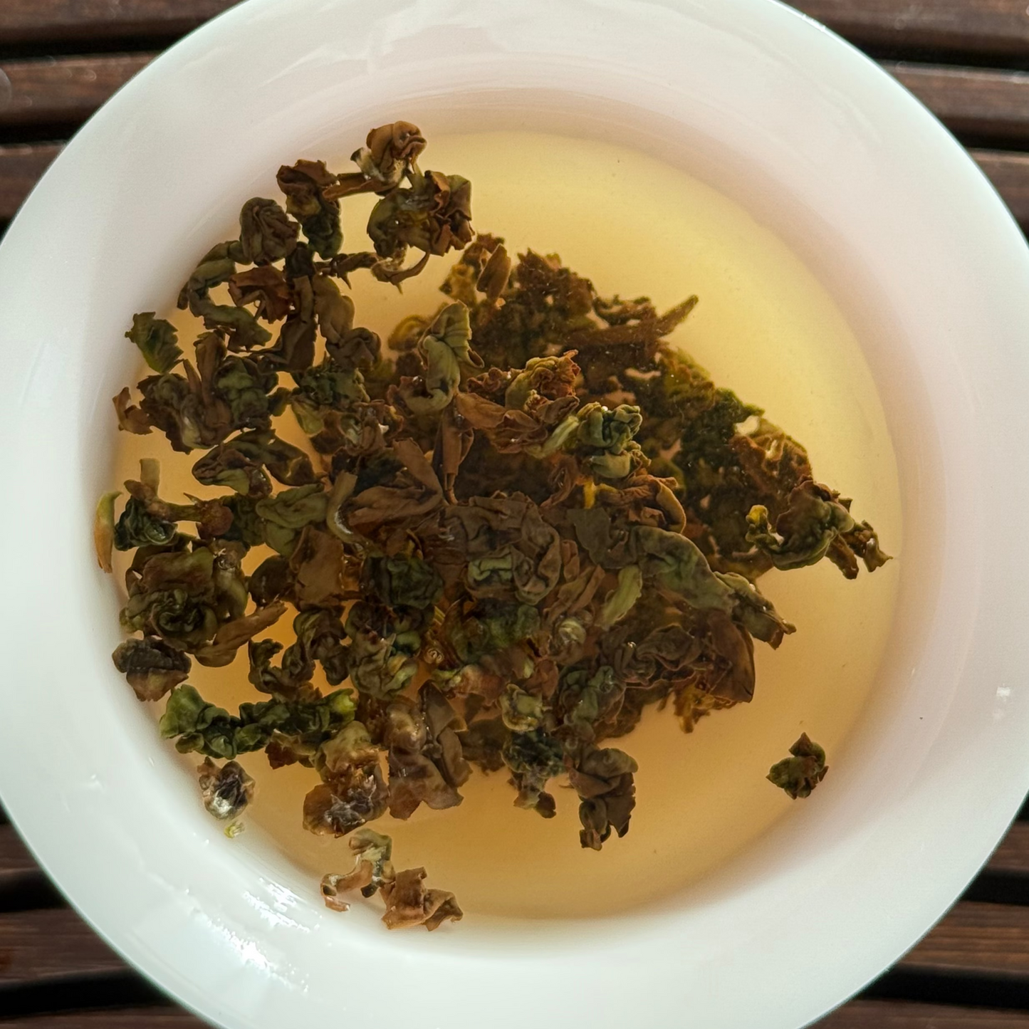 Tea leaves in a white bowl on a wooden surface